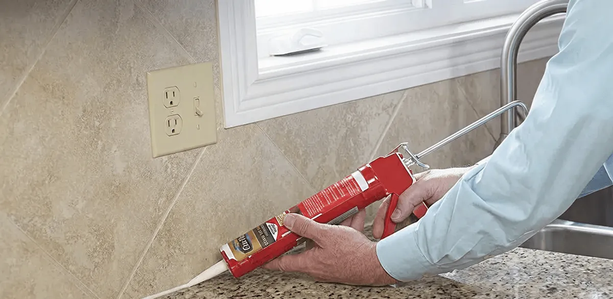 Handyman applying caulk along a kitchen backsplash and countertop seam in Glendale, AZ